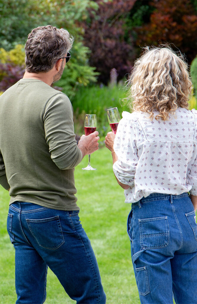 couple standing on lawn with wine glasses in hand